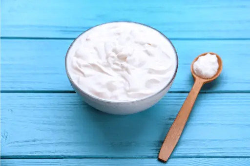 Bowl with yogurt on wooden background