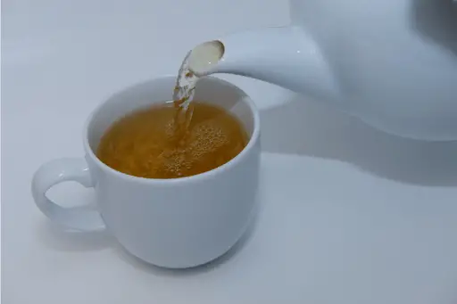 Person pouring green tea in a cup