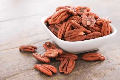 Pecan nuts in bowl over wooden table