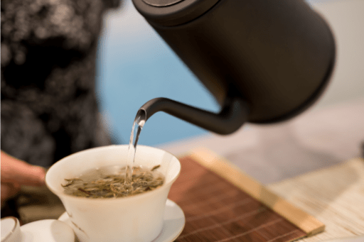 Pouring hot water over green tea leaves