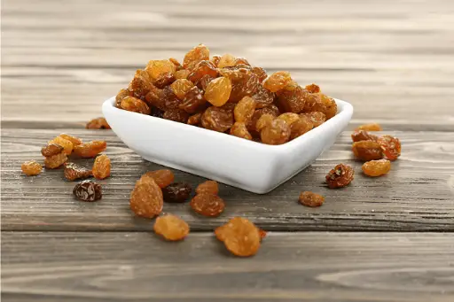 Raisins in Saucer on Wooden Table