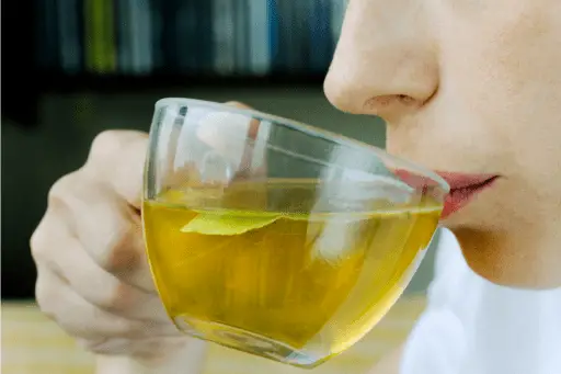 A women taking sip from green tea cup