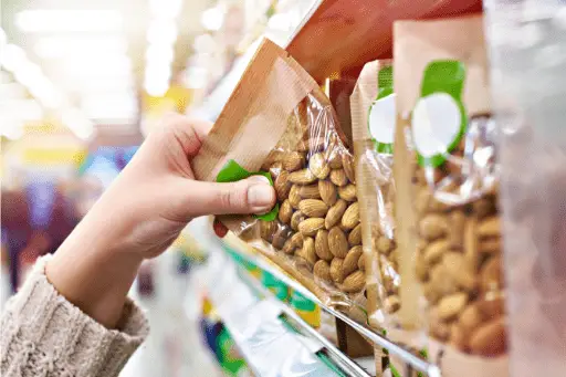 Female hand choosing almonds in store