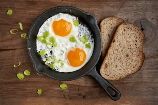 Egg omlet in pan with brown bread