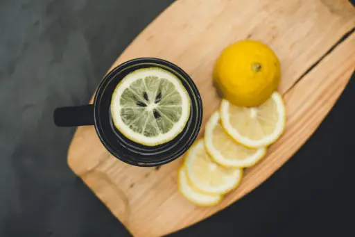 Lemon water and lemons on wooden board
