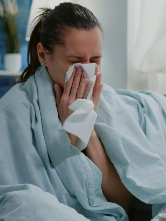 Sick woman using tissue to blow runny nose having cold